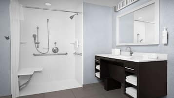Un baño moderno con ducha a ras de suelo, tocador con espejo y perchero.