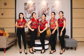 A group of five individuals in a modern interior with a sofa, round coffee table, and decorative wall art.