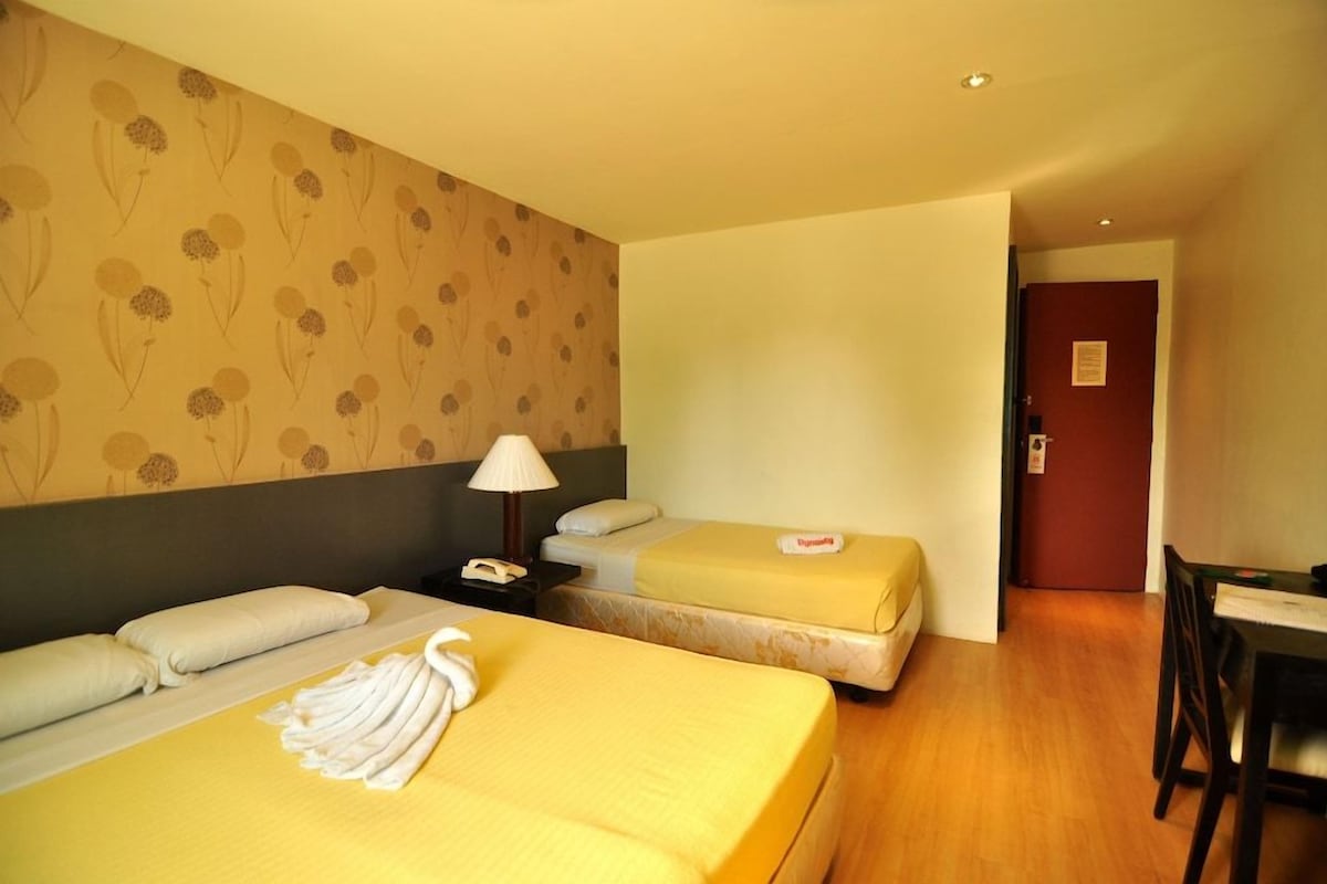 Una habitación de hotel con dos camas, un escritorio, una silla, una lámpara y una puerta.