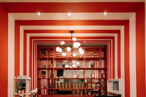 A room with a red and white striped wall, a chandelier, and shelves with various items.