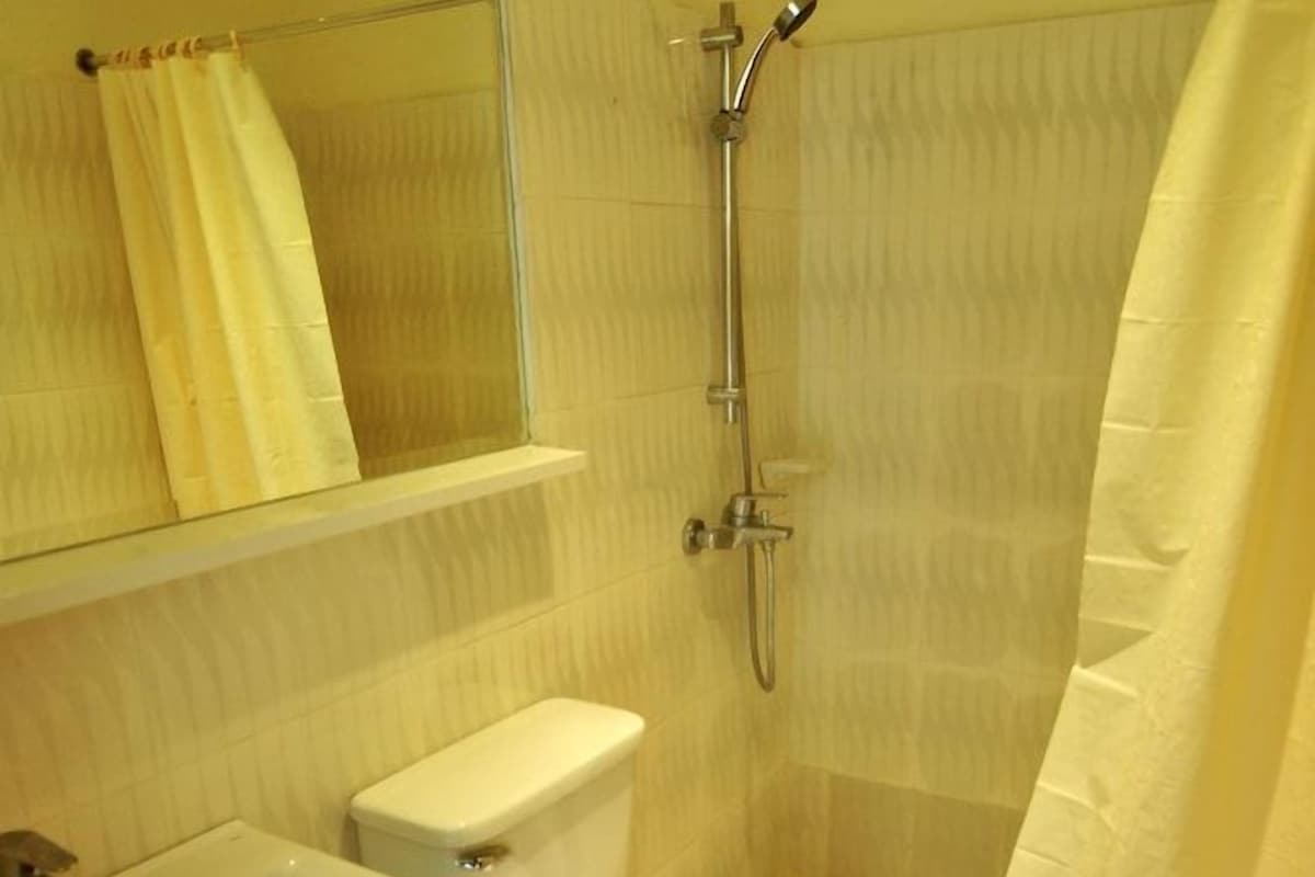 A bathroom with a toilet, sink, shower, and a mirror.