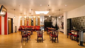 Un intérieur de restaurant moderne avec un plancher en bois, des sièges rembourrés de couleur rouge et des luminaires suspendus.