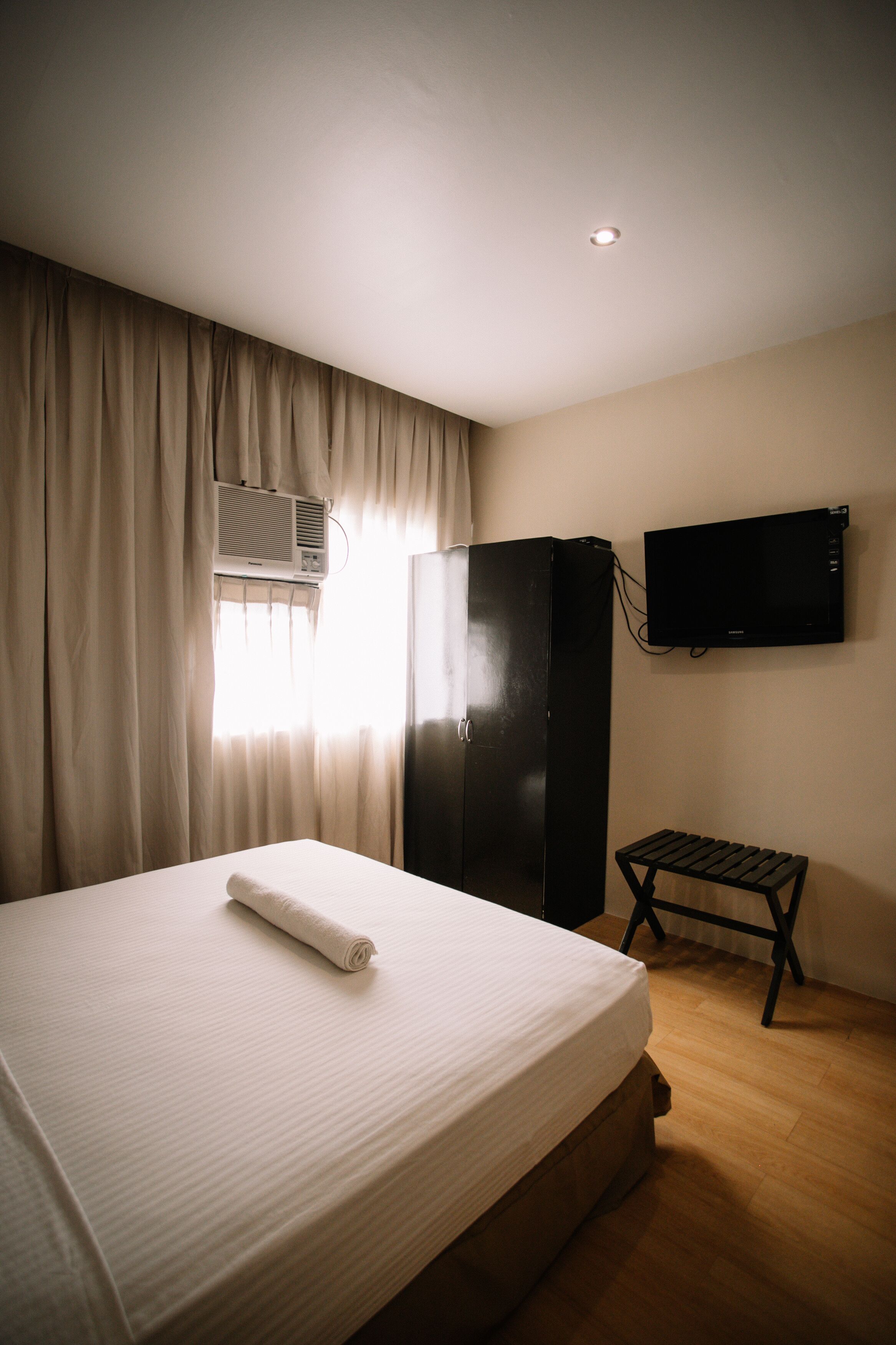 Una habitación de hotel con una cama, un escritorio, un televisor y un equipo de aire acondicionado.