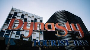 Une enseigne d’hôtel avec le nom « Dynasty Tourist Inn » écrit en grandes lettres.