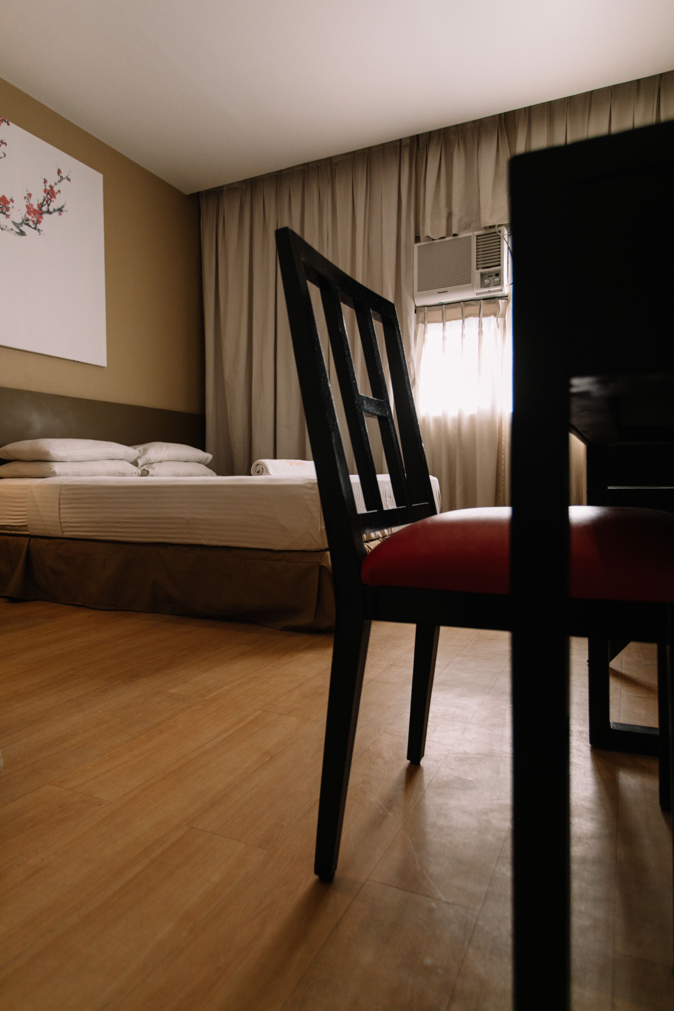 Una habitación de hotel con una cama, una silla y un equipo de aire acondicionado.