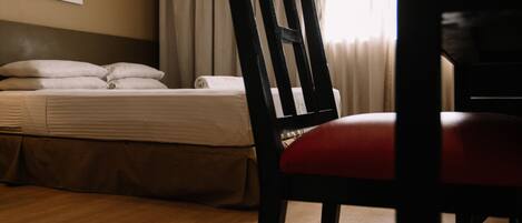 Una habitación de hotel con una cama, una silla y un equipo de aire acondicionado.