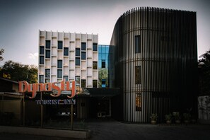 Experience the sleek, modern design of the Dynasty Hotel's exterior, featuring a striking vertical element and rectangular windows.