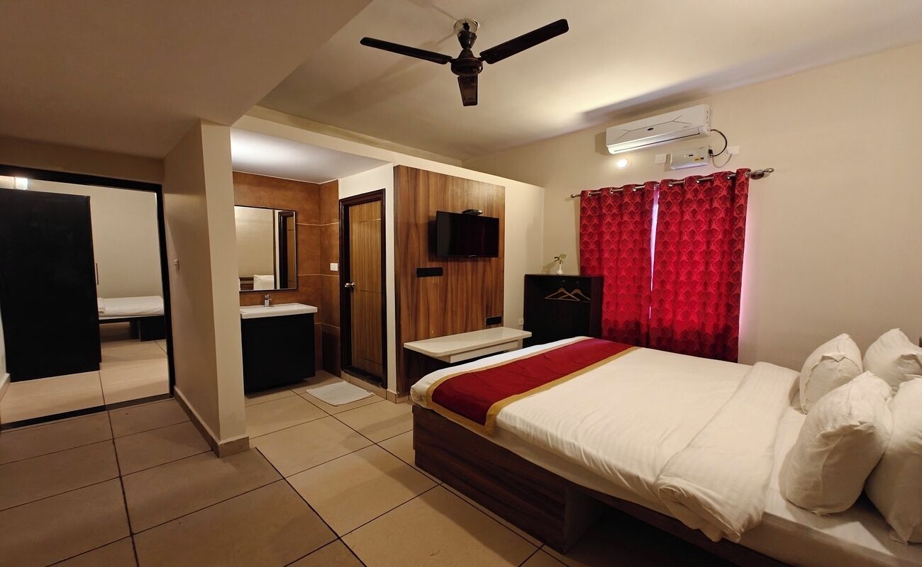 Una habitación de hotel con una cama, un tocador con espejo, un ventilador de techo y un televisor.