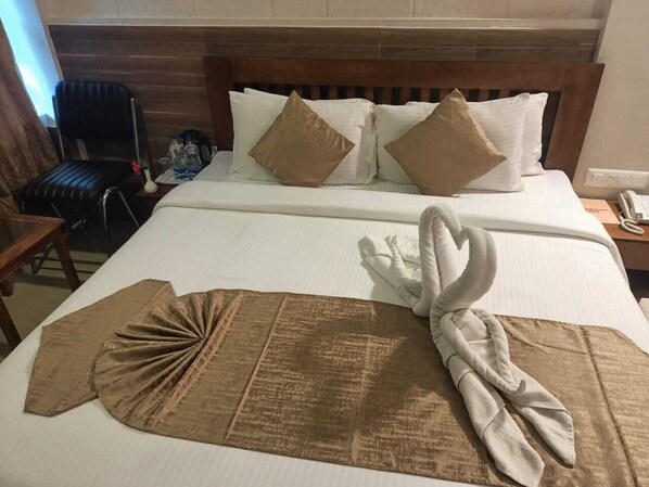 Habitación de hotel con una cama grande, un cabecero de madera y un par de toallas dispuestas en forma de cisne.