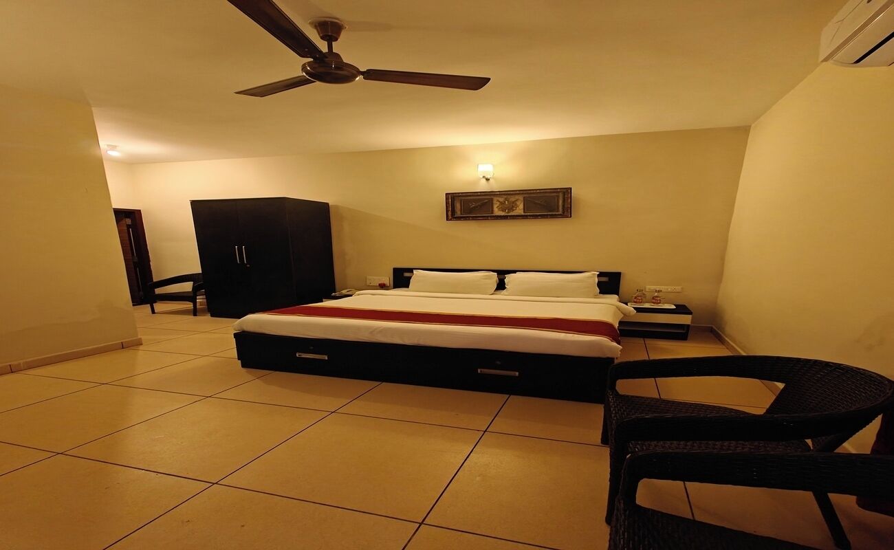 A bedroom with a bed, a ceiling fan, a nightstand, a chair, and a wardrobe.