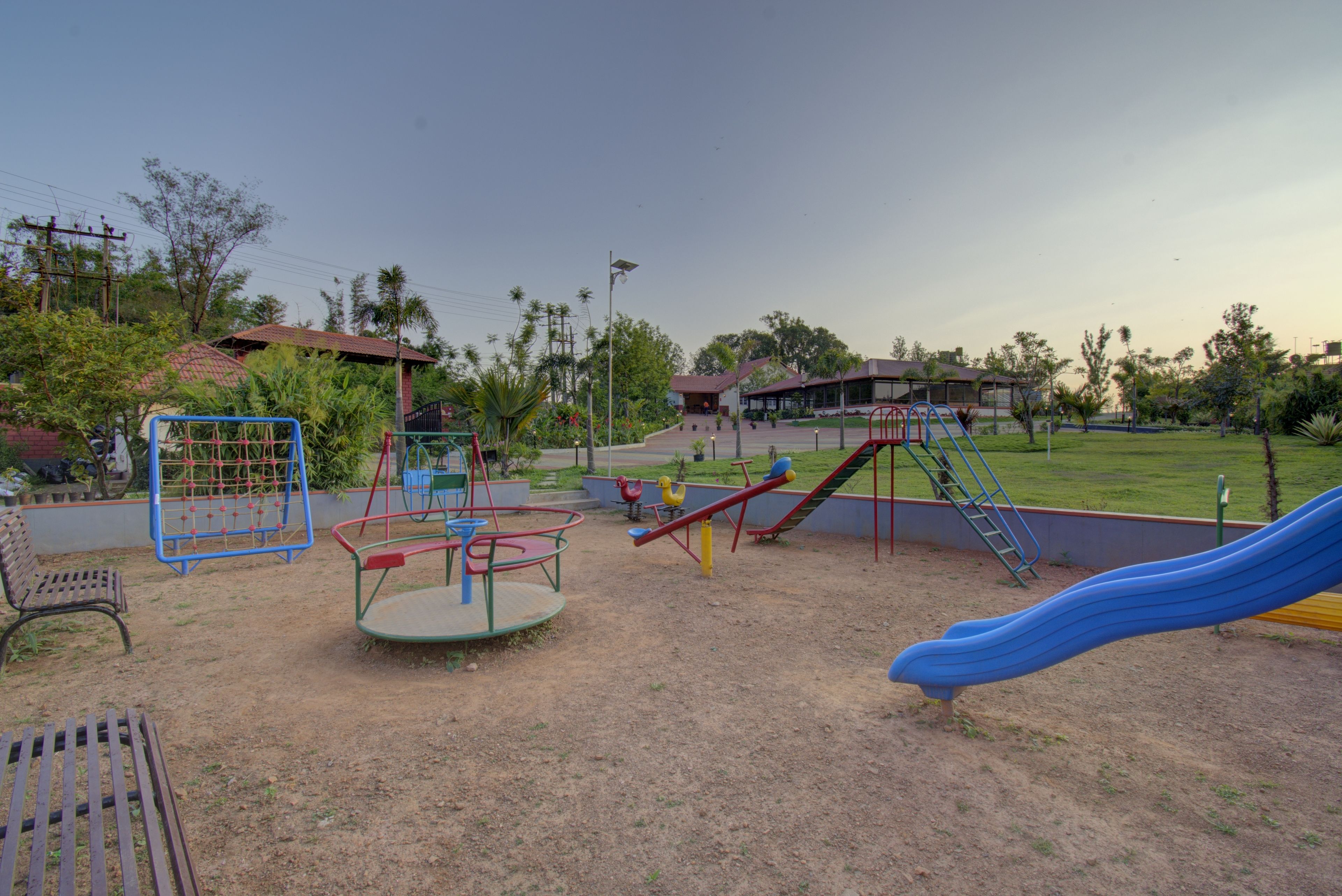 Un parque infantil con columpios, un tobogán y un carrusel.