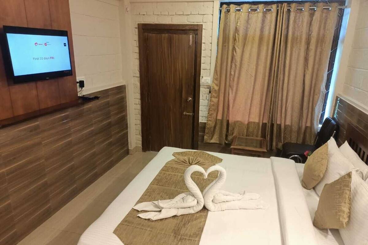 Habitación de hotel con cama, televisor en la pared y puerta de madera.