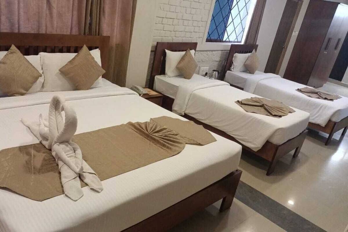 Una habitación de hotel con cuatro camas individuales, cada una con cabecero de madera y ropa de cama blanca.