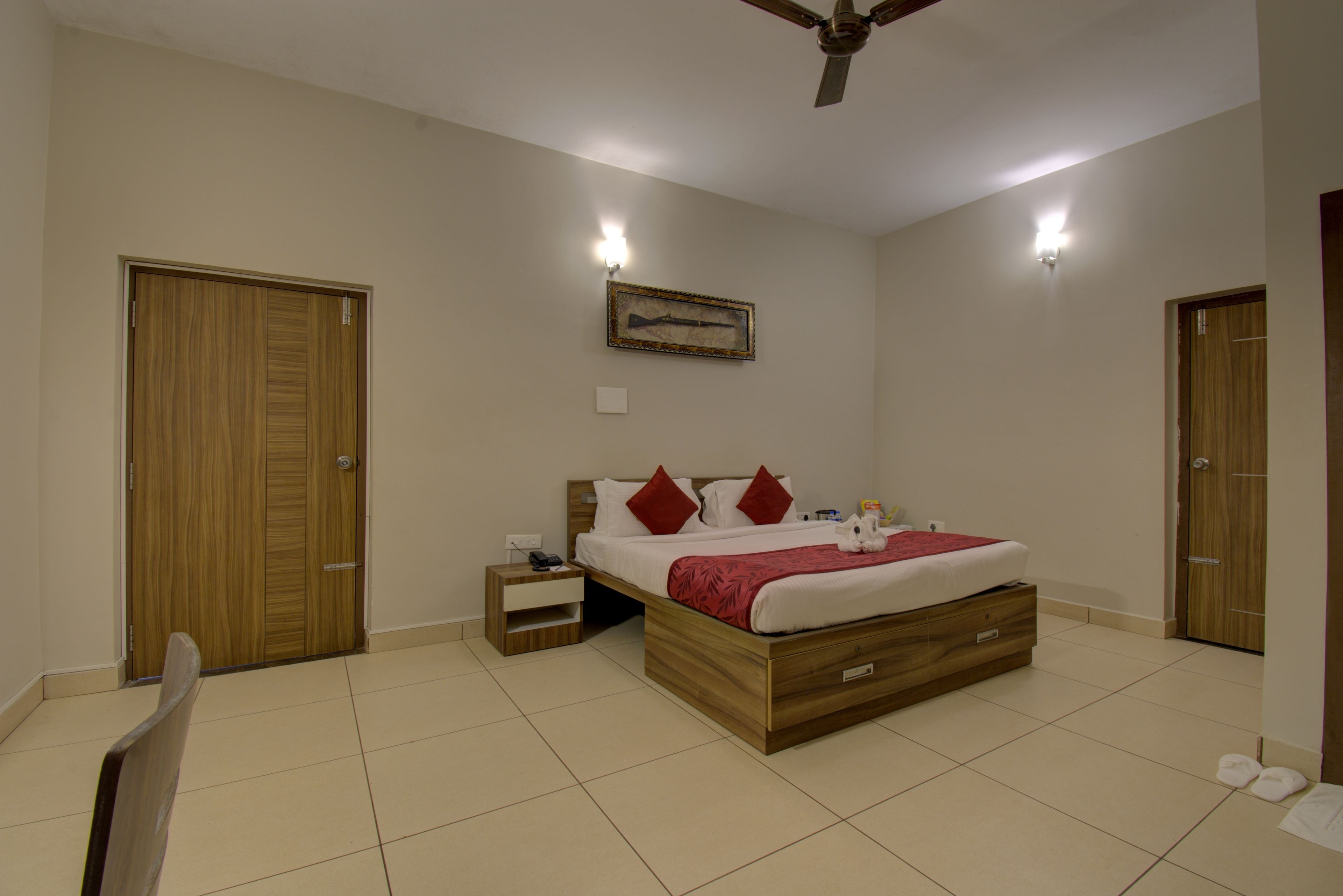 Un dormitorio con una cama de madera, una mesita de noche, un ventilador de techo y una lámpara de pared.