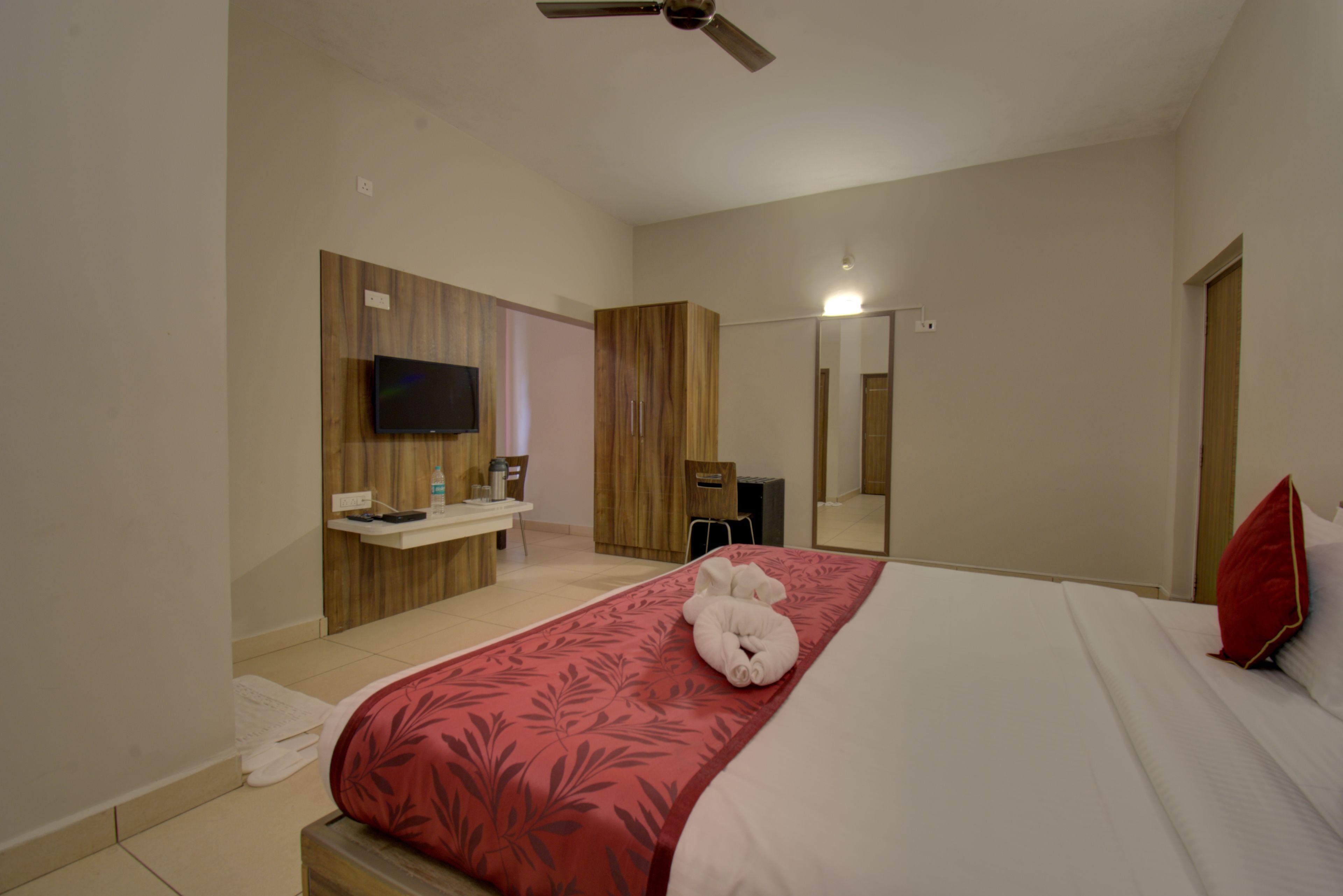 A hotel room with a bed, a television, a desk, and a wardrobe.