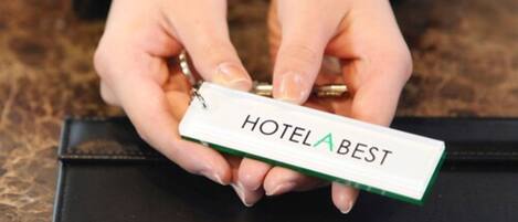 Une personne tenant une carte d’accès marquée du nom « HOTELABEST ».