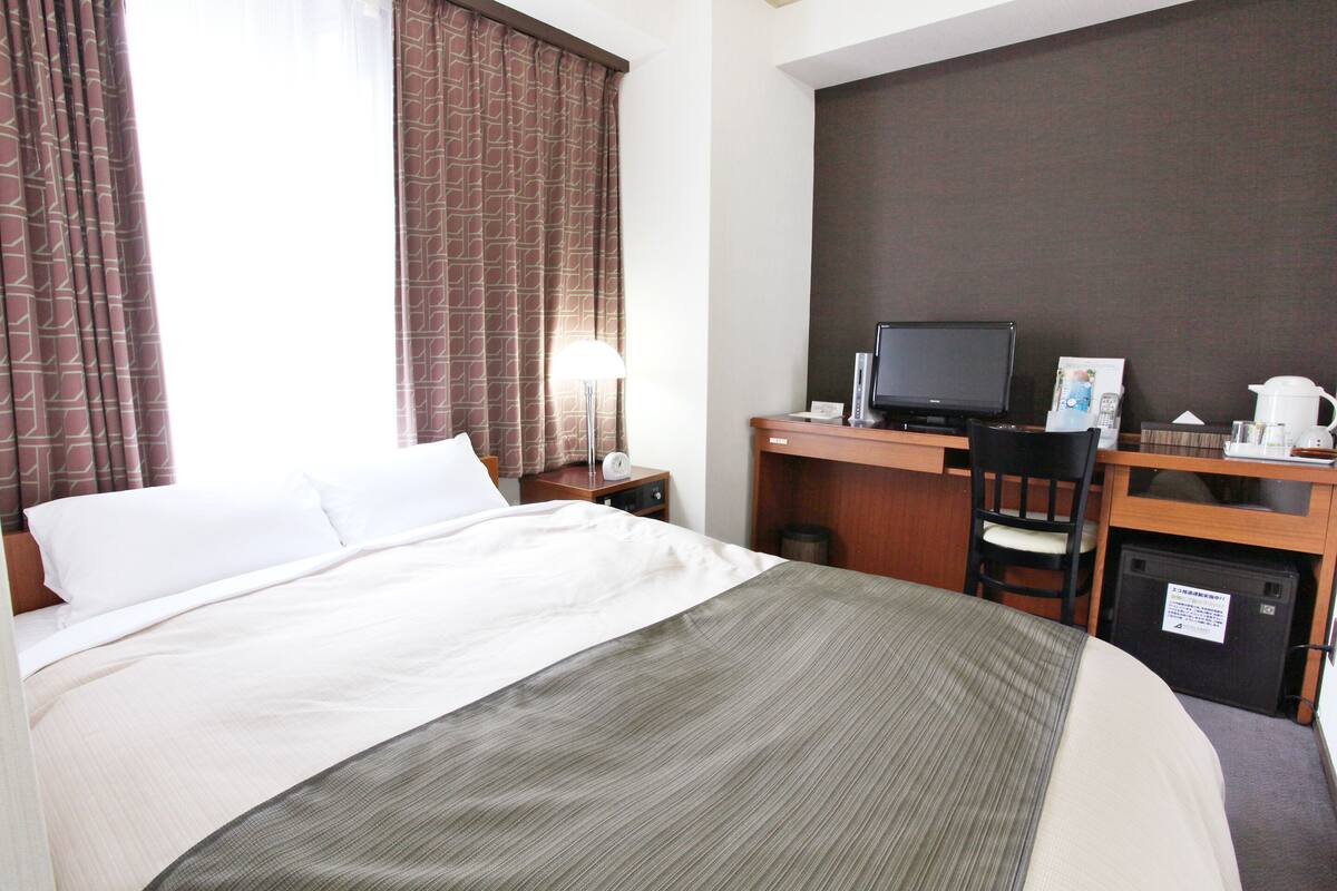 Une chambre d’hôtel équipée d’un lit, d’un bureau avec un ordinateur, d’une chaise et d’une machine à café.