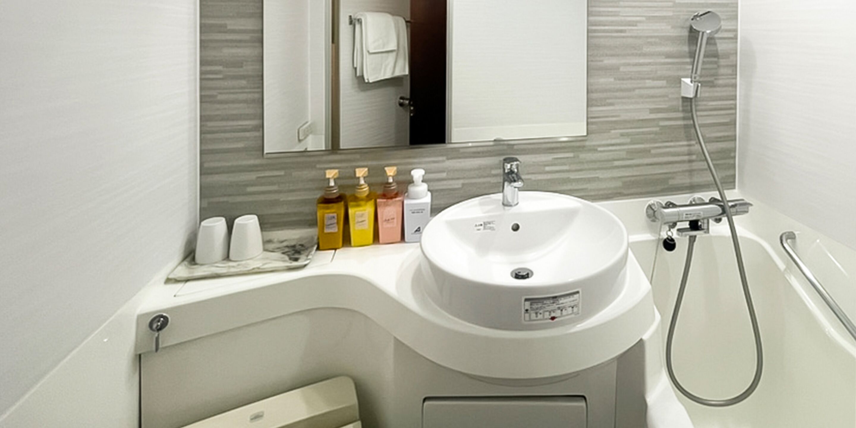 A bathroom with a sink, mirror, and shower.