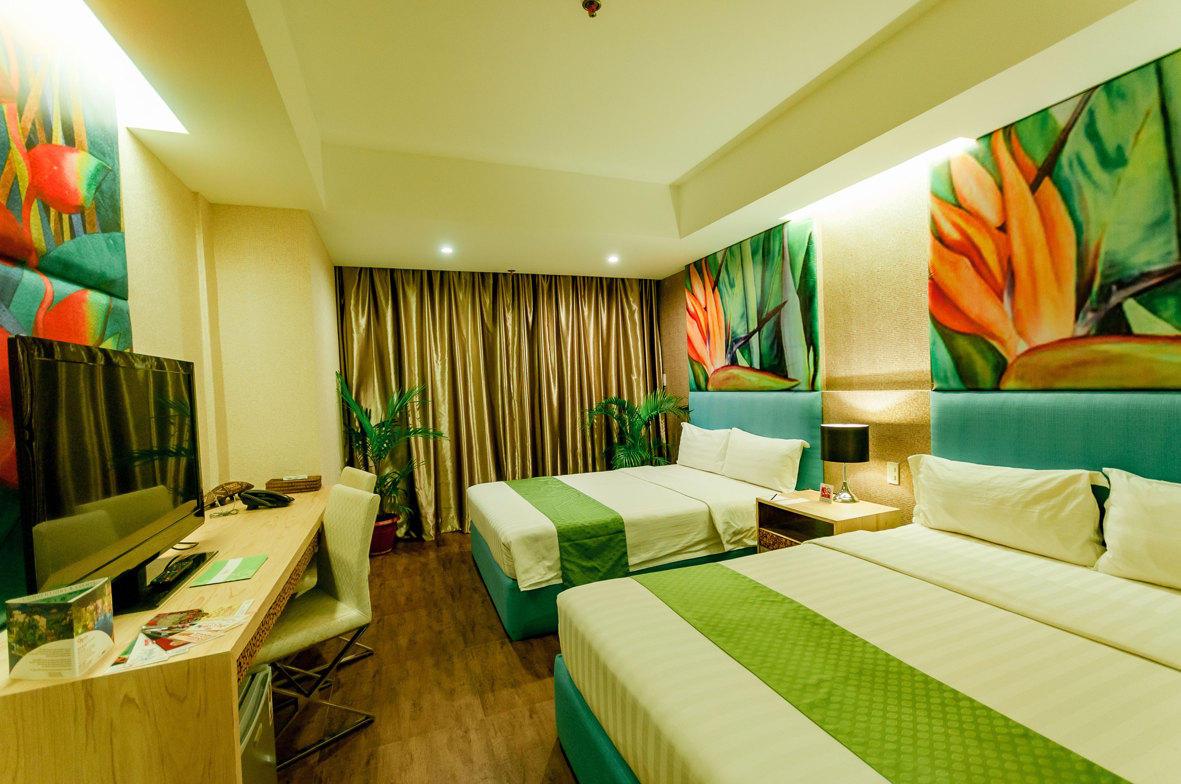 A hotel room with two beds, a desk with a computer, and a TV.