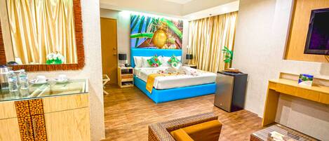 A hotel room with a bed, a desk, a mirror, a television, and a bathroom.