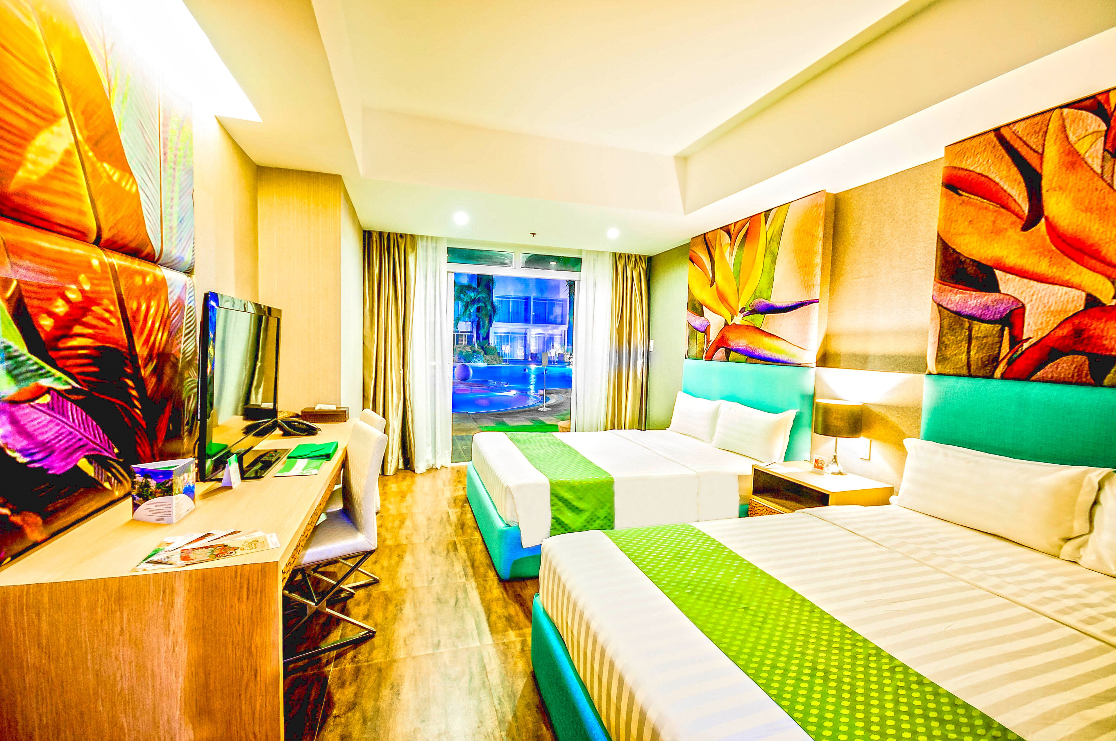 A hotel room with two beds, a desk, a chair, and a view of a pool.