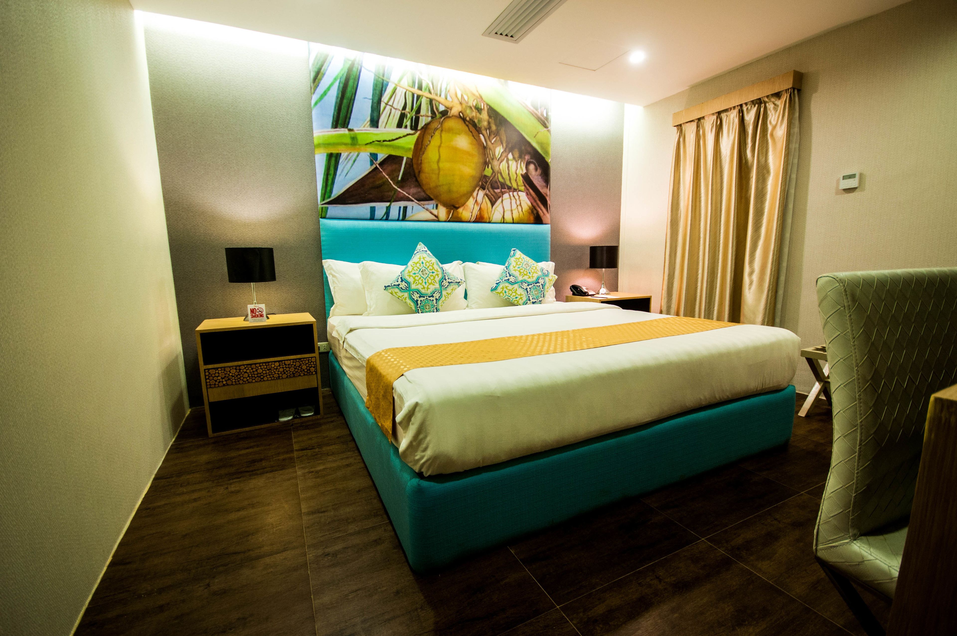 Une chambre d’hôtel avec un lit, une table de chevet, une chaise et une fresque murale.
