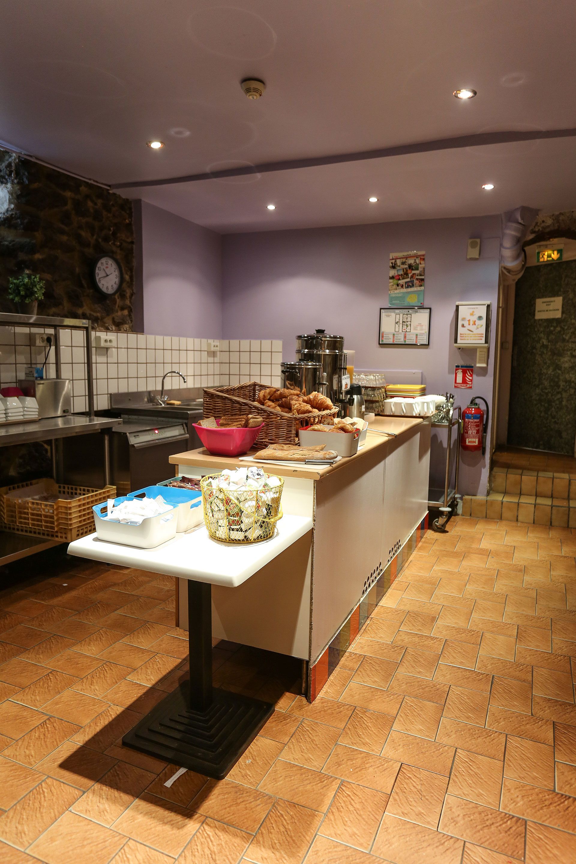 A kitchen area with a counter displaying various food items, a sink, and a fire extinguisher.