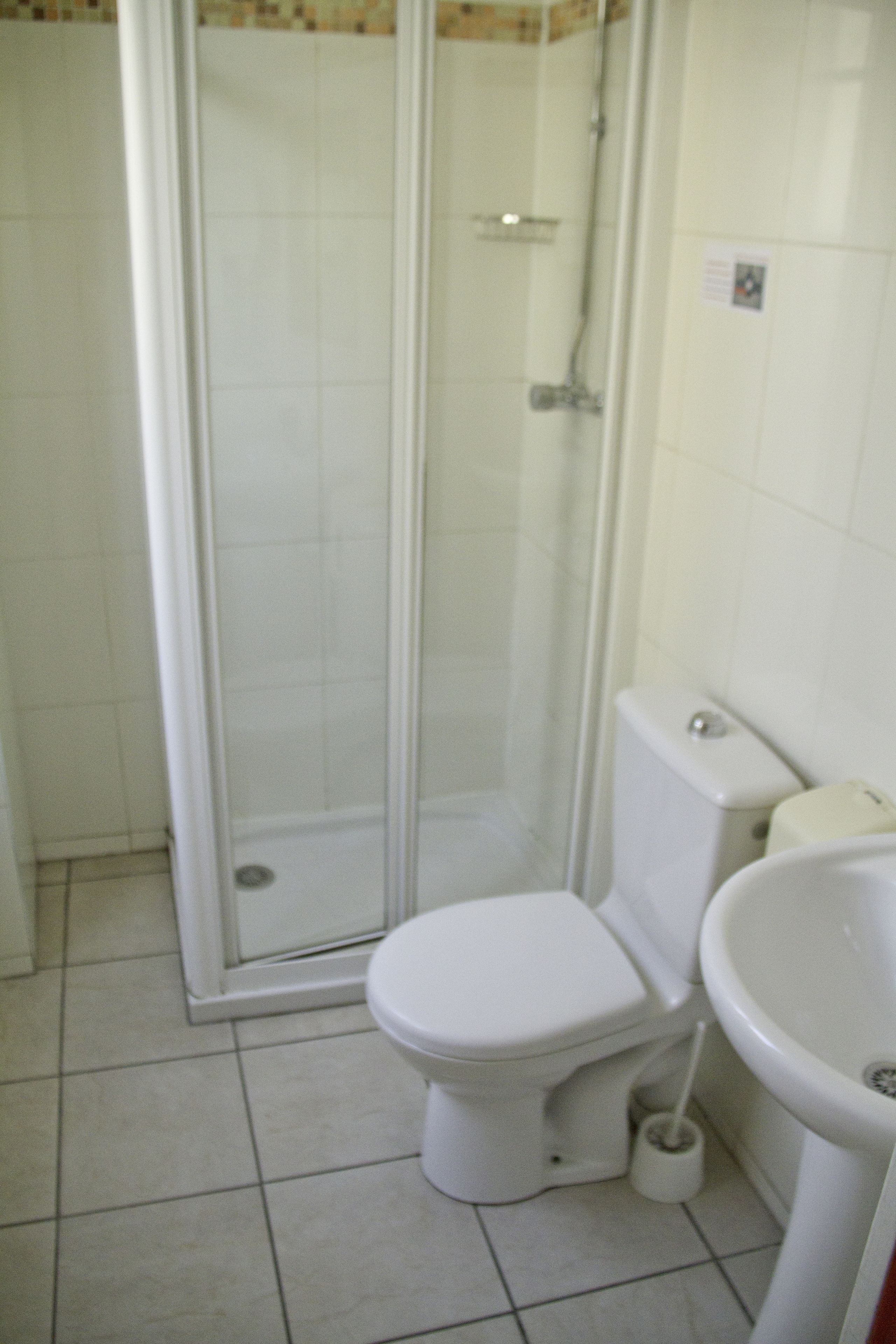 Un bagno con il water, un lavandino e uno spazio doccia con pareti in vetro.