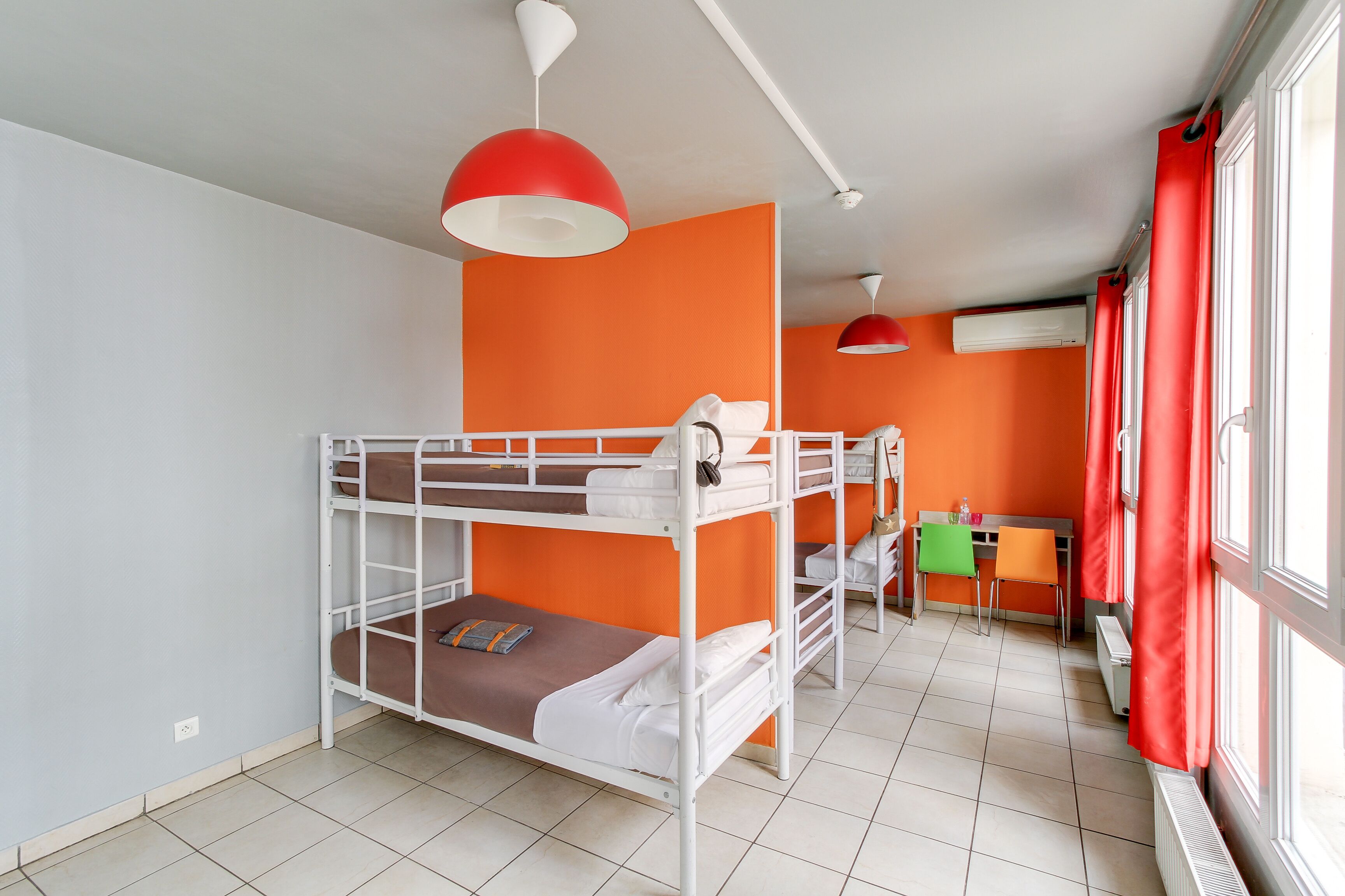 A dormitory room with bunk beds, a desk, and a chair.