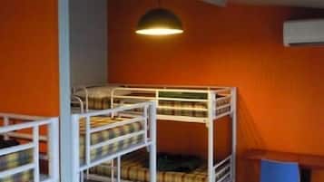 Habitación con literas, una pared naranja, un escritorio y una silla azul.