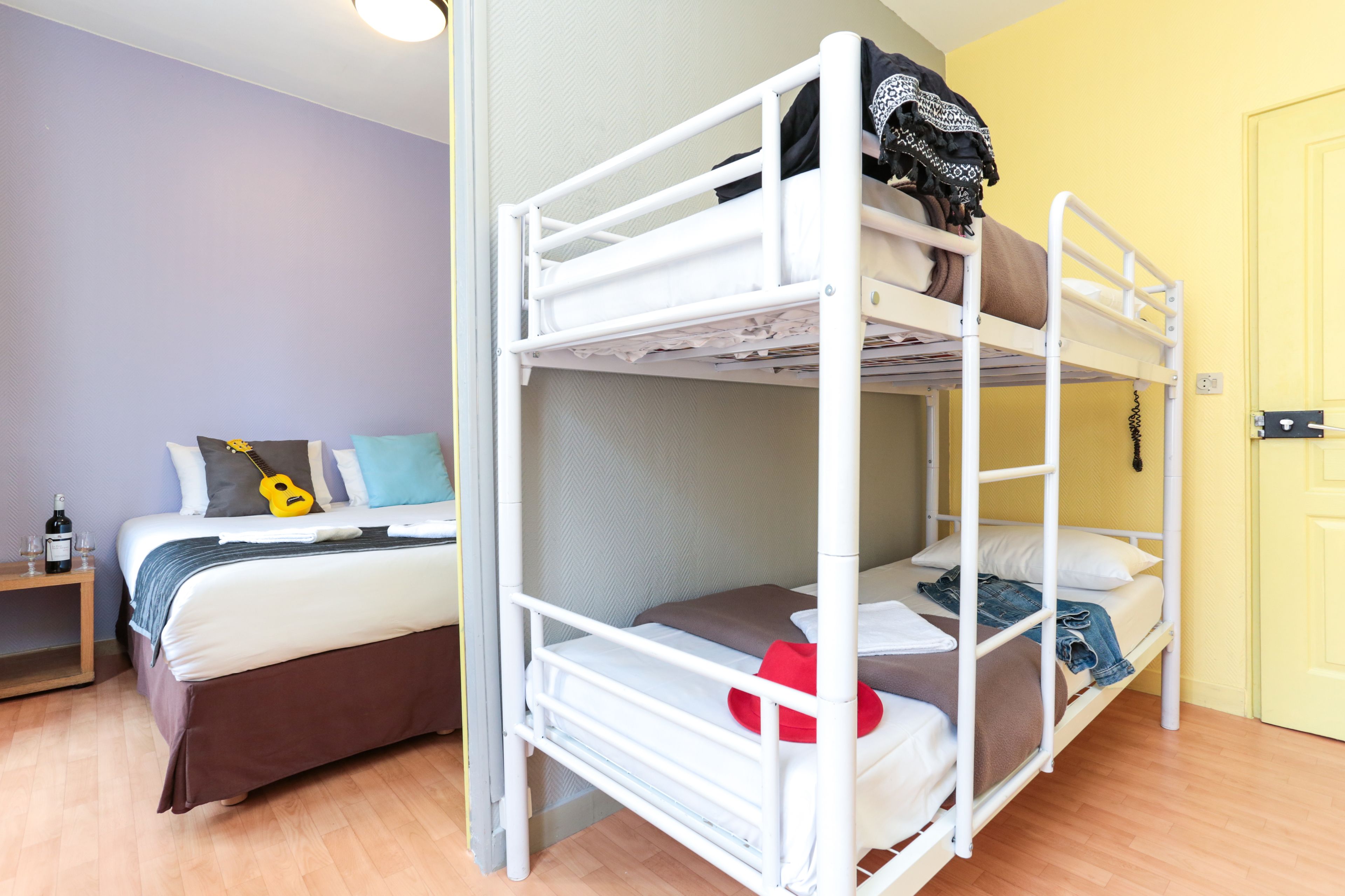 Une chambre avec un lit superposé, une table de chevet et une guitare posée sur le lit.