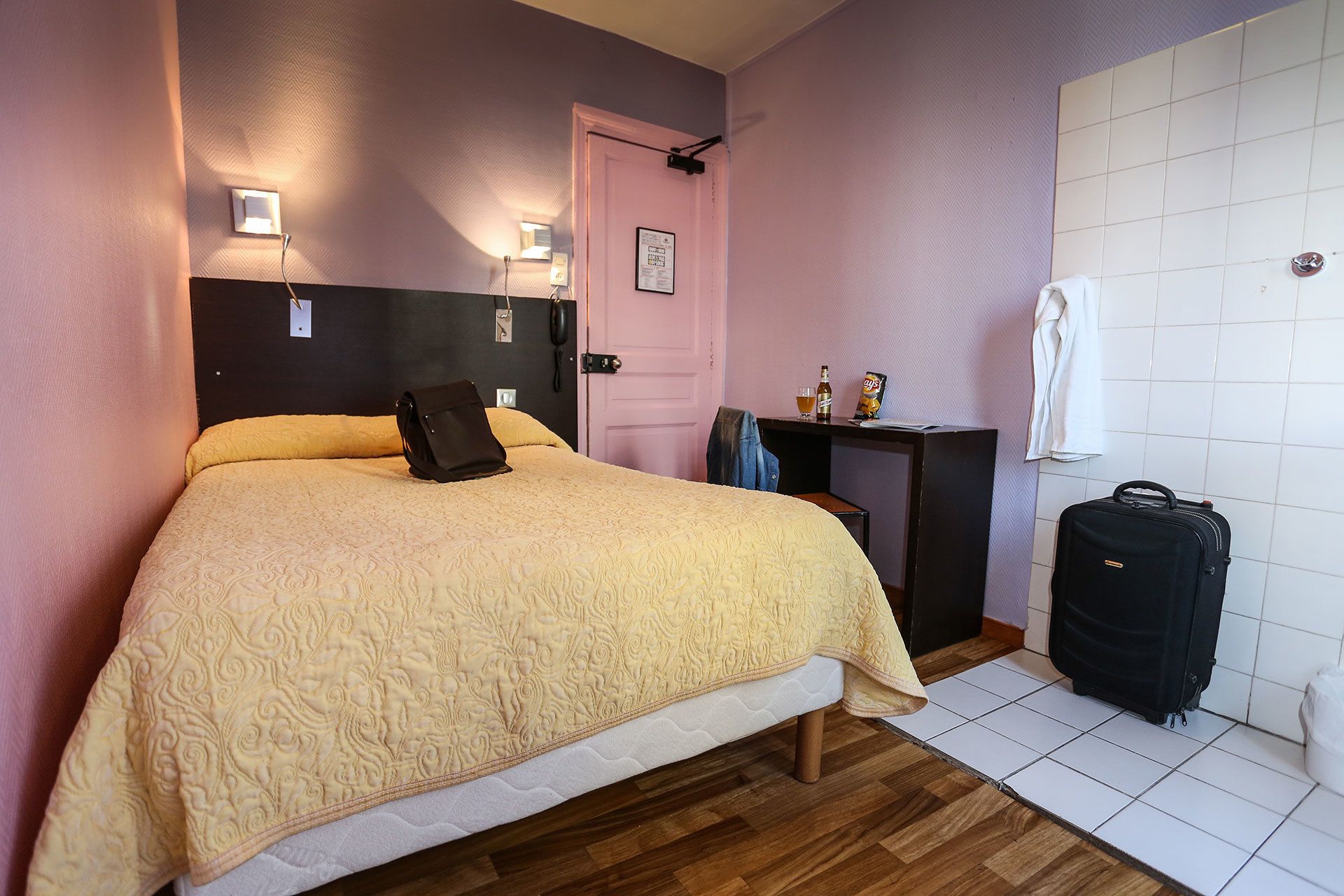 A bedroom with a bed, bedside table, and a suitcase.
