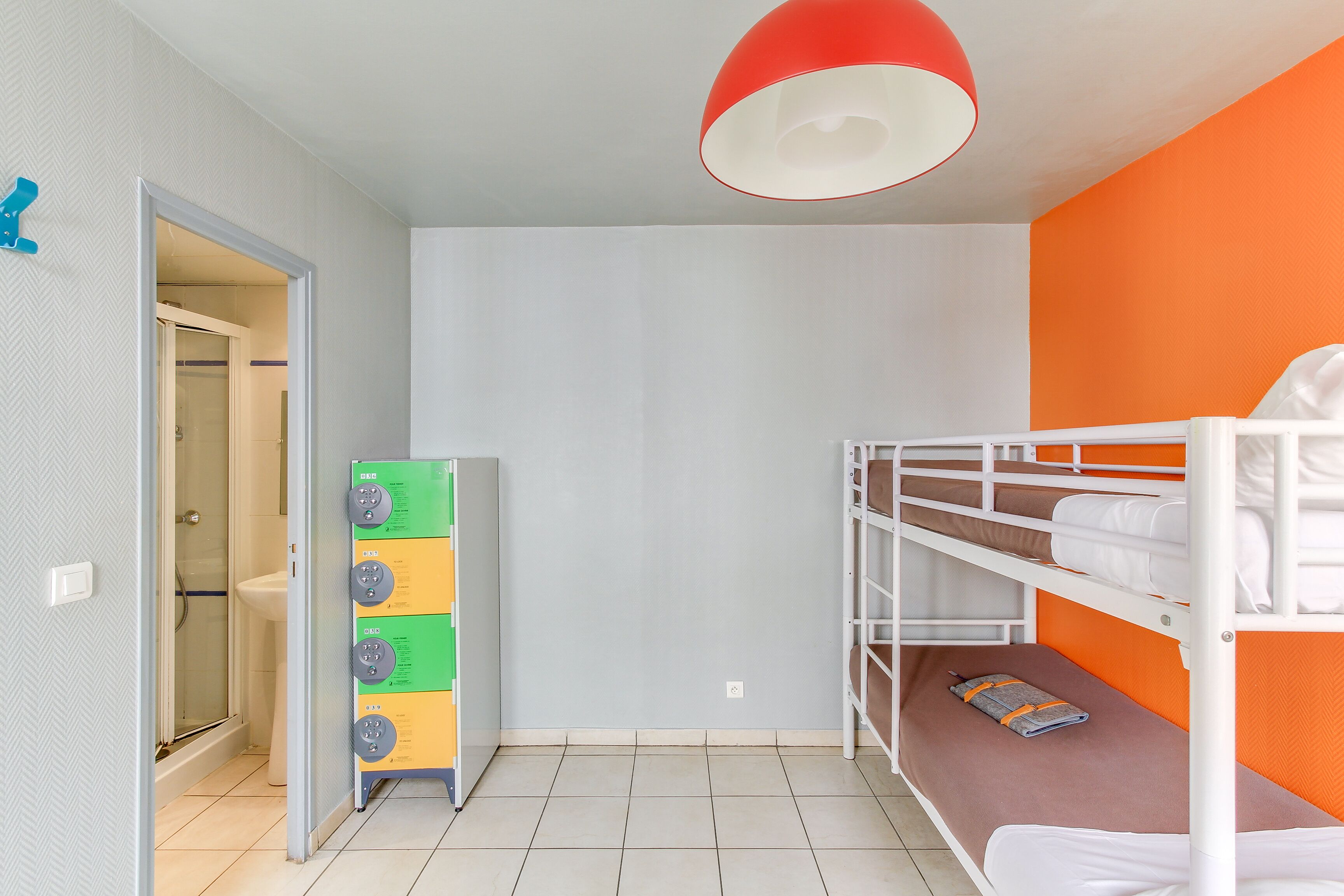 A room with bunk beds, a white door, a glass shower, and a red ceiling light.
