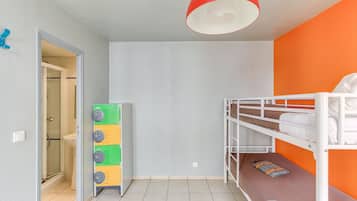 Ein Zimmer mit Etagenbetten, einer weißen Tür, einer Glasdusche und einer roten Deckenleuchte.