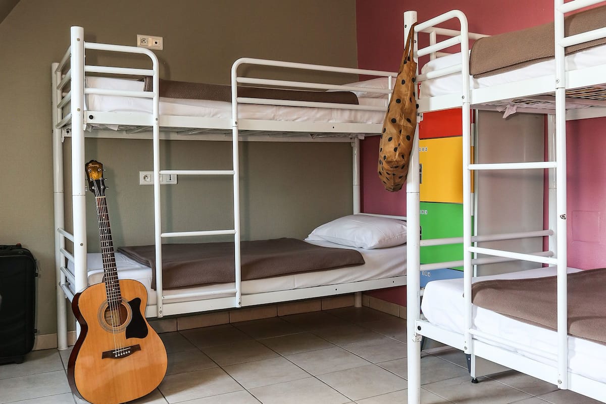 A dormitory room with bunk beds, a guitar, and a colorful storage unit.