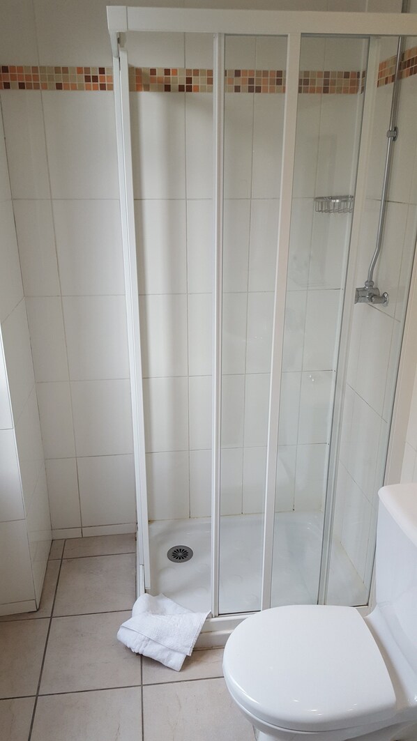 A bathroom with a glass-enclosed shower, a toilet, and a tiled floor. - Le Montclair Montmartre by River - Hostel (Paris)