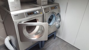 Une machine à laver à chargement frontal de qualité professionnelle, en acier inoxydable, dotée d’un écran numérique et d’un panneau de commande, ainsi qu’un sèche-linge avec une porte transparente.