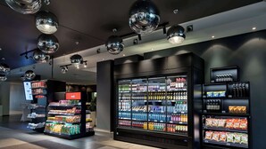A modern retail area with a large refrigerated display and shelves stocked with beverages and snacks. - Doubletree by Hilton Vienna Schonbrunn (Vienna)