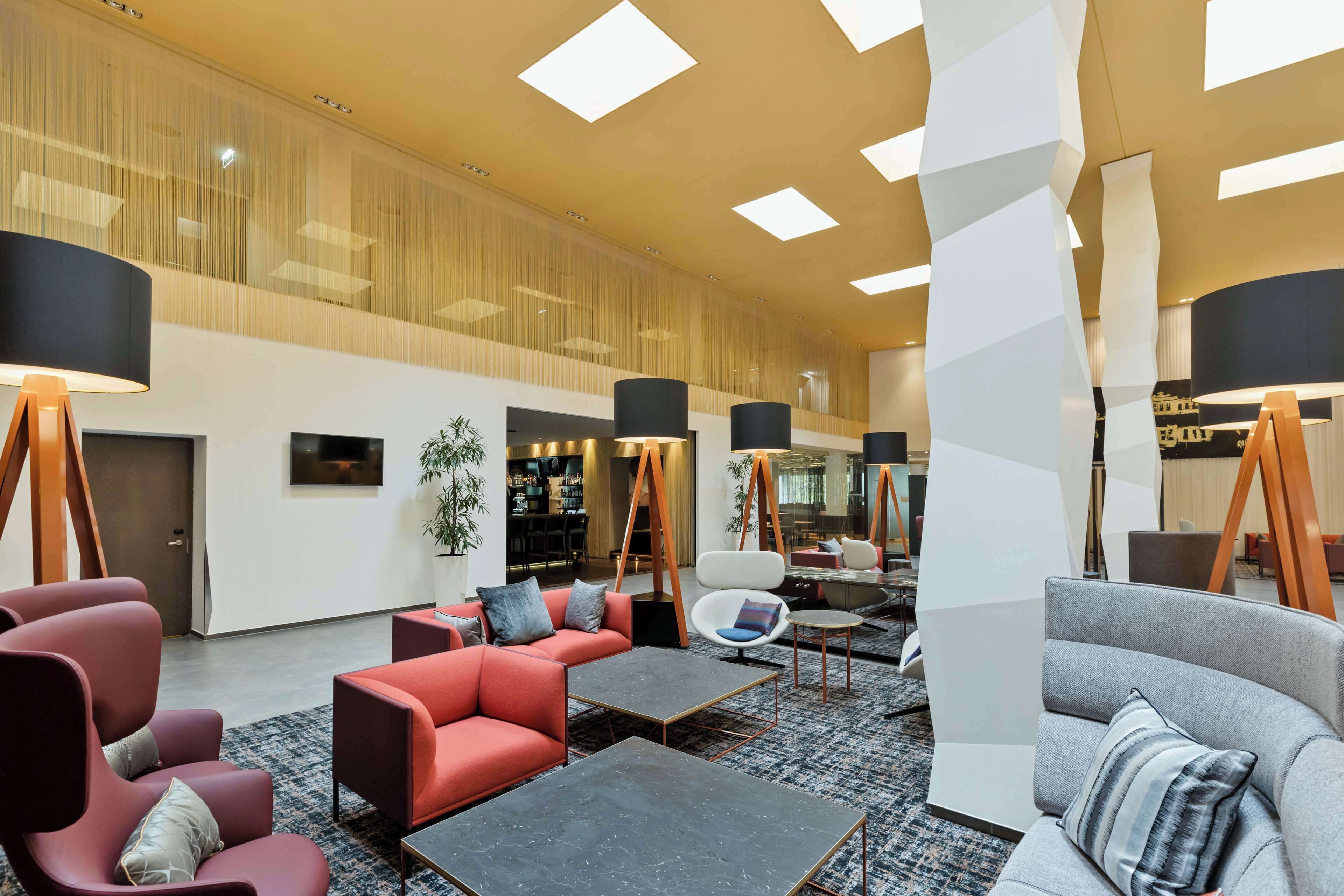 A modern lobby with seating areas, a bar, and a staircase.