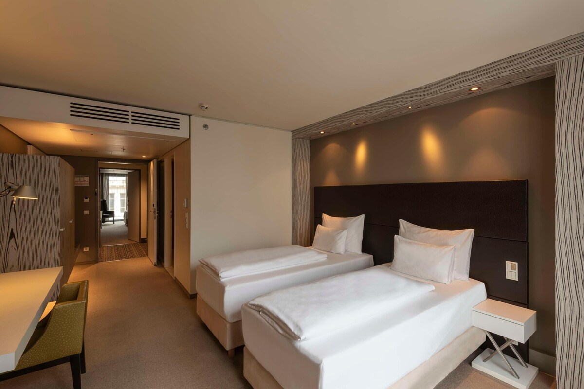 Una habitación de hotel con dos camas individuales, un escritorio y una silla.