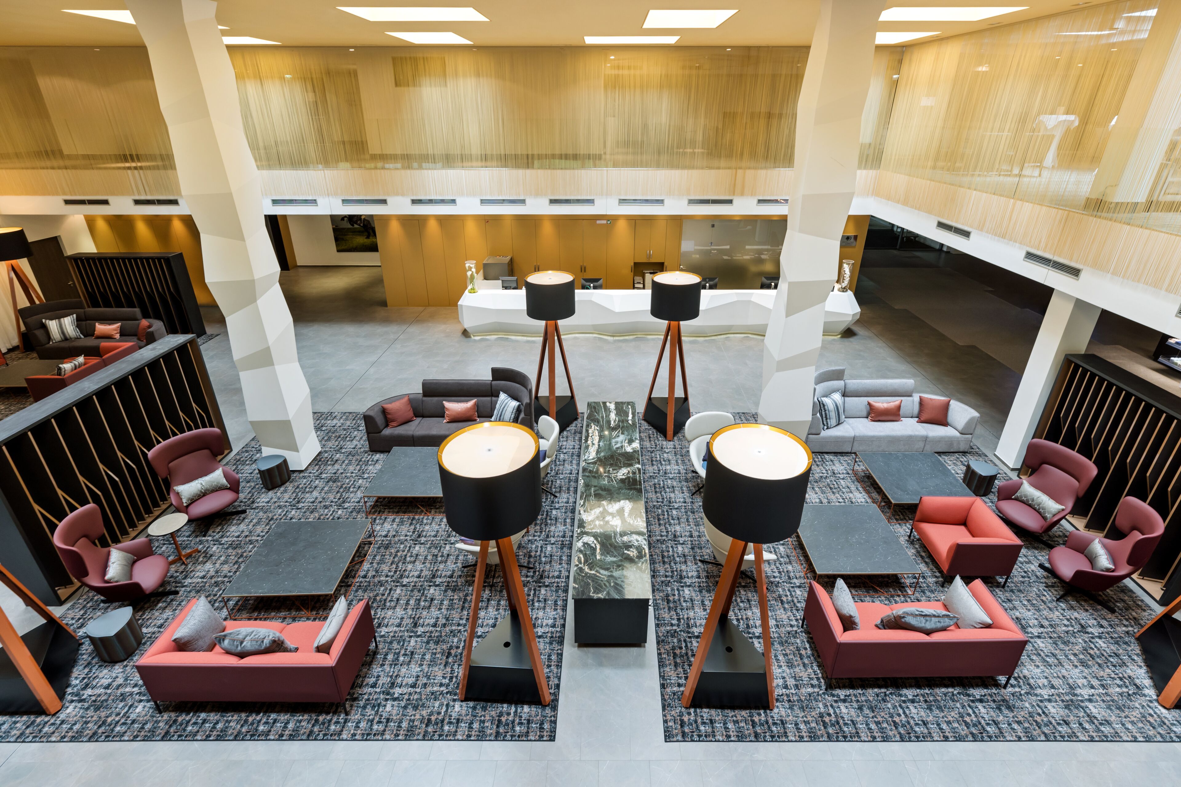 A spacious lobby with modern seating arrangements, a central coffee table, and a reception desk.