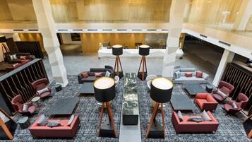 Eine großzügige Lobby mit modernen Sitzgelegenheiten, einem zentralen Couchtisch und einer Rezeption.