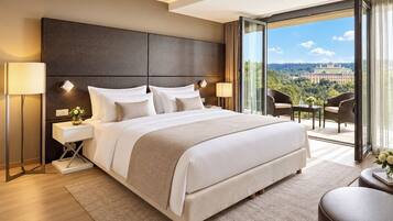 A modern hotel room with a large bed, a nightstand, a desk, and a balcony with a view.
