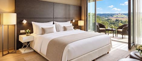 A modern hotel room with a large bed, a nightstand, a desk, and a balcony with a view.