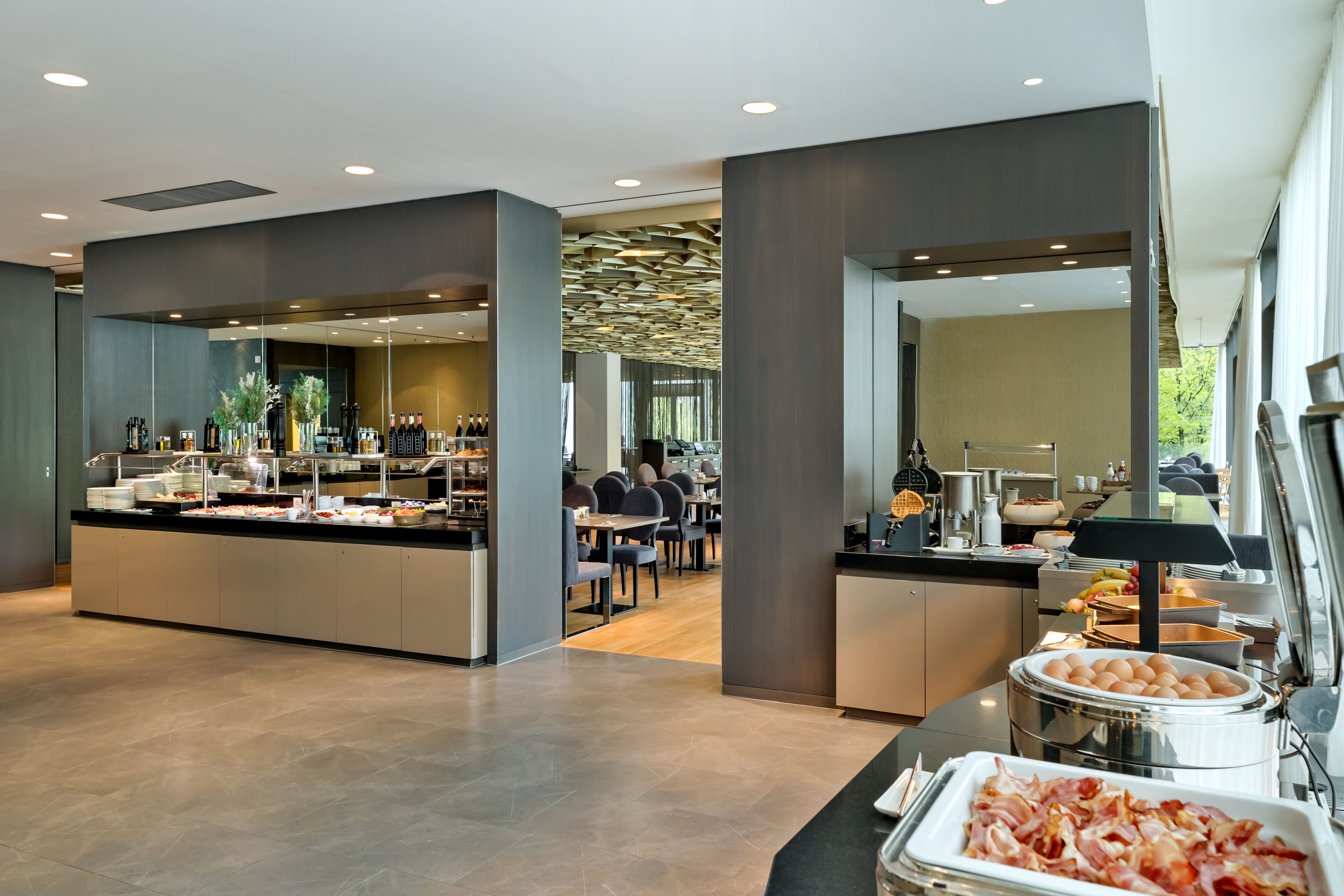 A modern hotel lobby with a buffet area, seating, and a view of the dining area.