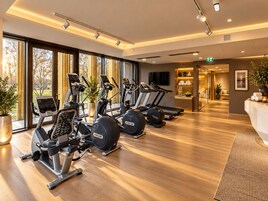 Uma academia com várias máquinas de exercício, janelas amplas e uma área de recepção.