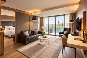 A modern hotel room with a bed, a sofa, a dining table, and a TV. - Grand Hotel Palace Schönbrunn (Vienna)