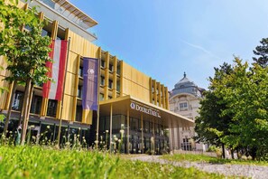 A modern hotel with a prominent "DoubleTree" sign, a glass facade, and a classical building in the background. - Doubletree by Hilton Vienna Schonbrunn (Vienna)