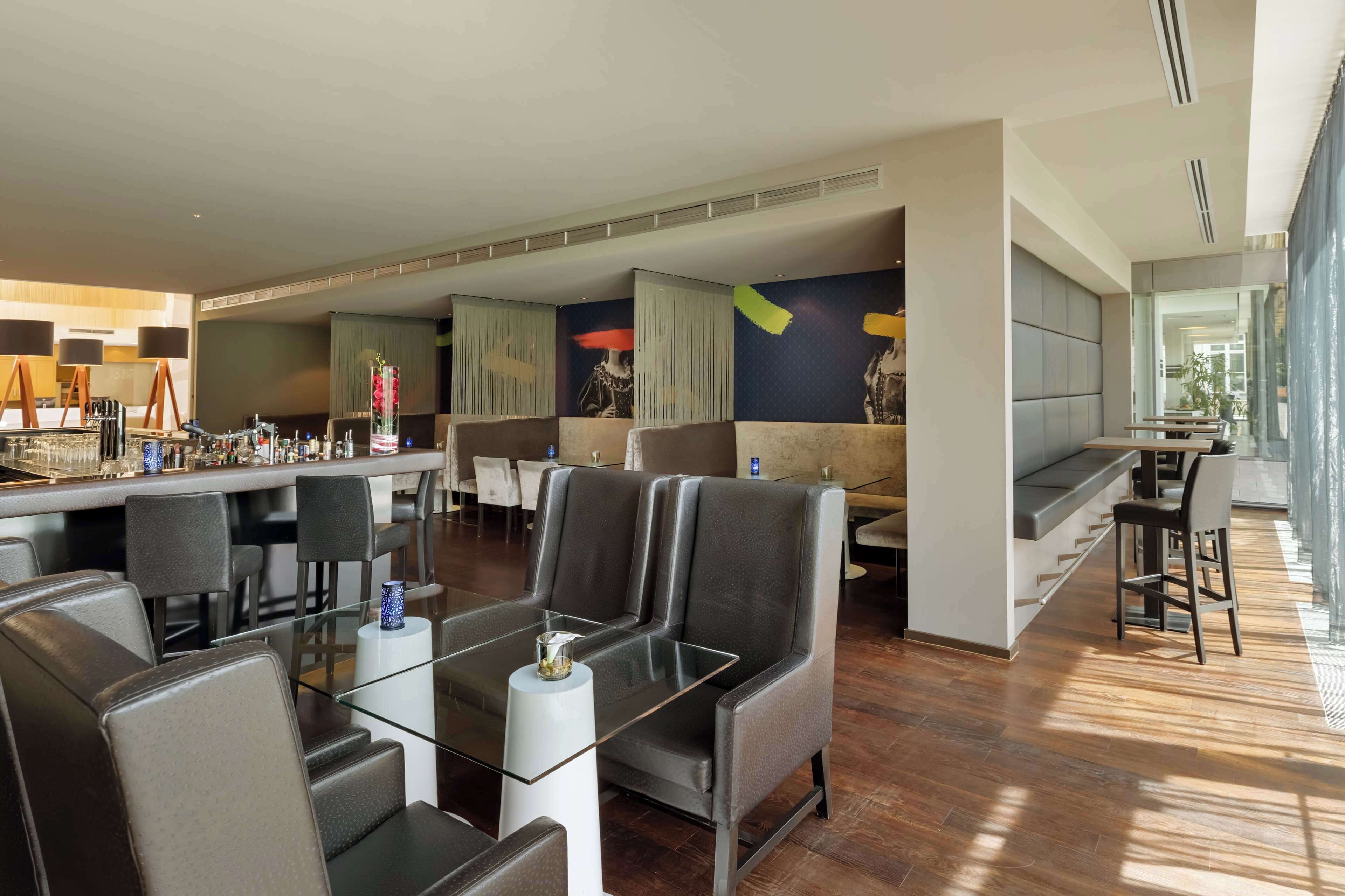 A modern lounge area with leather seating, a glass coffee table, and a bar with various amenities.