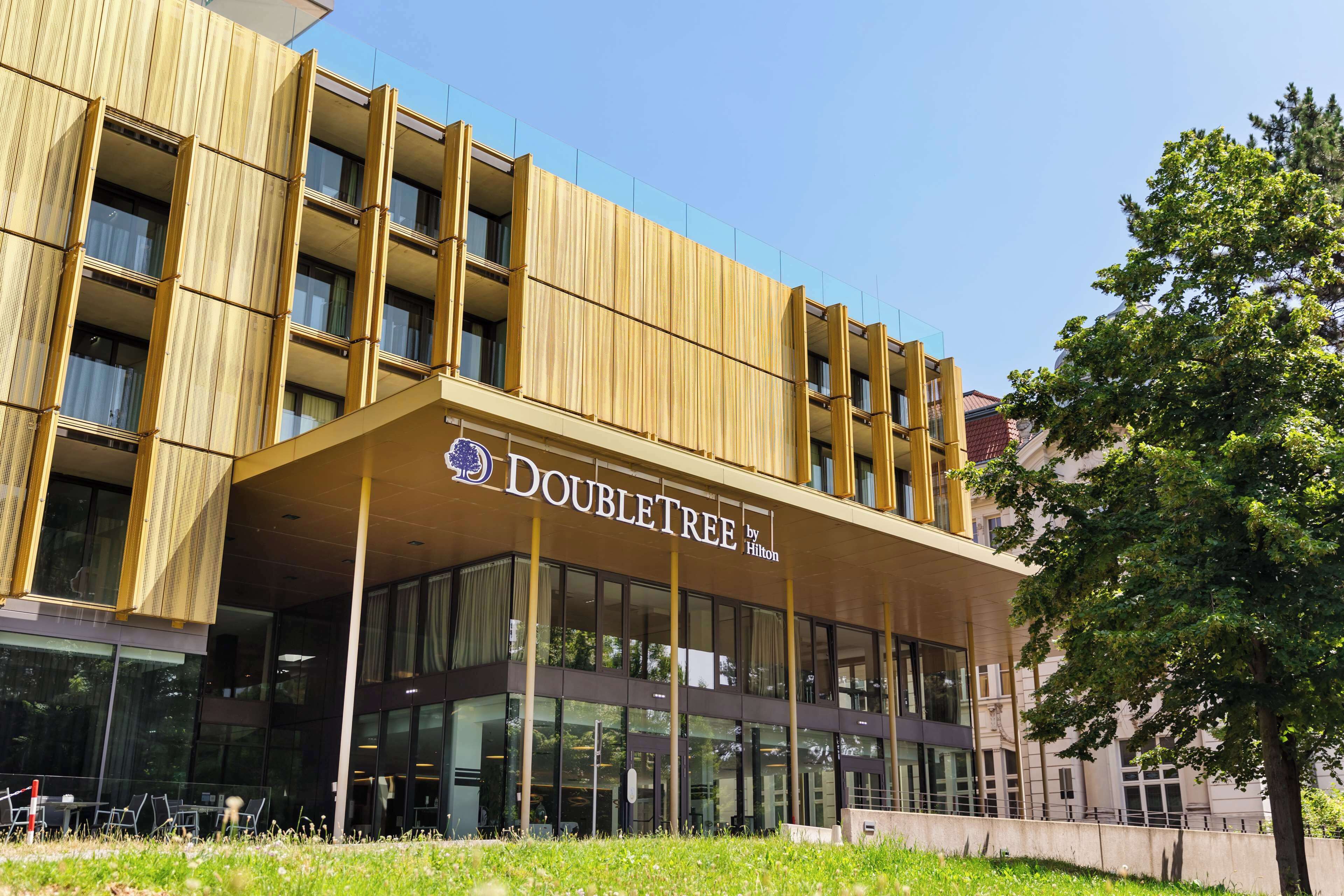 Un hôtel DoubleTree by Hilton au design moderne, doté de grandes fenêtres et offrant une vue sur un ciel dégagé.